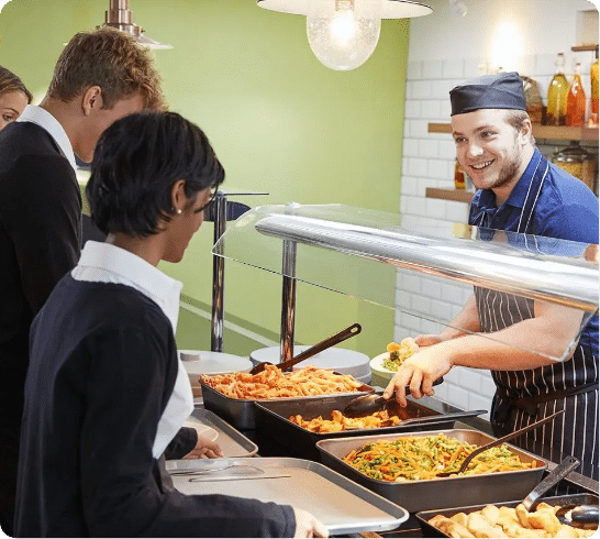 School catering staff serving students lunch.